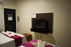 a room with two beds and a flat screen tv at Pequena Sereia Guriri in São Mateus