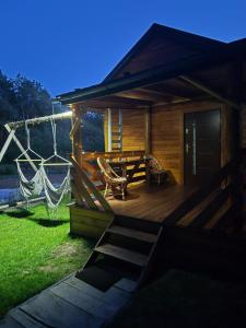 a cabin with a wooden deck with a table and chairs at Pod lasem Celina Burda in Majdan Sopocki