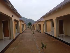 an empty alley between buildings with mountains in the background at Wayekha Hotels in Kasungu