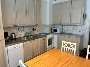 a kitchen with white cabinets and a wooden floor at Huoneisto Vipunen in Savonlinna +3 photos