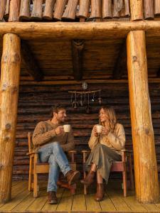 a man and woman sitting in a cabin drinking coffee at Guest house Oaze in Miglāni