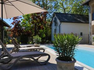 two lounge chairs and an umbrella next to a pool at Mirage Apartments & Pool - Balatonboglar in Balatonboglár