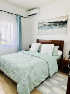 a bedroom with a bed with a green comforter at Villa Almadies in Pointe-Noire