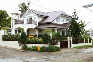 a white house with a fence in front of it at Balay Pahuwai Bed & Breakfast in Tagaytay