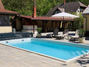 a swimming pool in a yard with chairs and an umbrella at Mirage Apartments & Pool - Balatonboglar in Balatonboglár