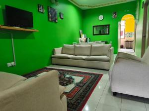 a green living room with two couches and a tv at Irman Homestay Pendang in Pendang