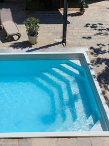 a large blue swimming pool sitting next to a chair at Mirage Apartments & Pool - Balatonboglar in Balatonboglár +32 photos