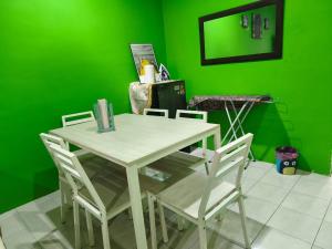 a table and chairs in a green room with a green wall at Irman Homestay Pendang in Pendang