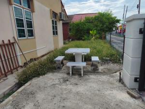 a picnic table and two benches in front of a building at Irman Homestay Pendang in Pendang