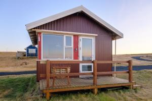 a small house with a large window on a field at Ofanleiti Cottages in Vestmannaeyjar