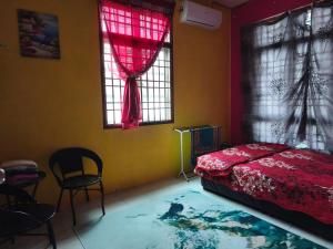 a bedroom with a bed and two chairs and windows at Irman Homestay Pendang in Pendang