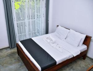 a bed with white sheets and white pillows and a window at Eco Bless Inn in Kandy