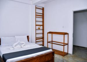 a bedroom with a bed with white sheets and a shelf at Eco Bless Inn in Kandy