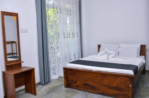a bedroom with a bed and a mirror and a window at Eco Bless Inn in Kandy +2 photos