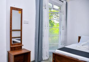 a bedroom with a bed and a mirror and a window at Eco Bless Inn in Kandy
