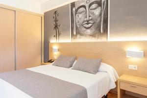 ein Schlafzimmer mit einem Bett und einem Gemälde einer Frau in der Unterkunft Hotel Golden in Benidorm