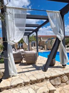 a patio with a pergola and a pool at Opg Pelejš in Pag