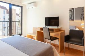 ein Schlafzimmer mit Schreibtisch, Computer und Fernseher in der Unterkunft Hotel Golden in Benidorm