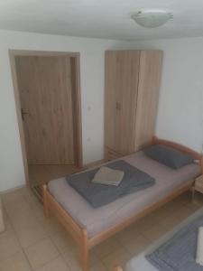a small bedroom with a bed and wooden cabinets at Room AIKA in Tolmin