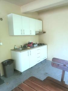 a kitchen with white cabinets and a sink and a trash can at Room AIKA in Tolmin