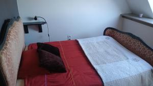 a bed in a room with a red blanket at Au cottage normand in Saint-James
