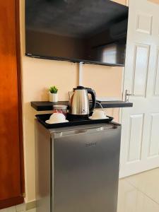 a kitchen with a tea kettle on top of a refrigerator at Aurum Stays in Gaborone