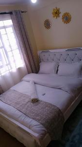 a bedroom with a large white bed with a window at Cozy cloud in Ruiru
