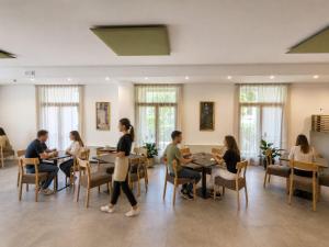 a group of people sitting at tables in a restaurant at Hotel Vela in Nago-Torbole