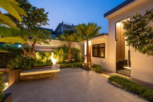 a courtyard of a house with a bench and trees at Continuum Hotel Udonthani in Udon Thani