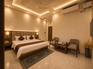 a bedroom with a bed and two chairs and a table at Hotel JB Square Ayodhya Near Ram Mandir, Airport & Ayodhya Cantt in Ayodhya