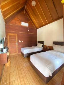 a bedroom with two beds and a television in it at Villa GHANIA in Labuanbalat