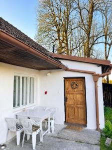 a white house with white chairs and a wooden door at Chaloupka na Perkách in Zahrádky