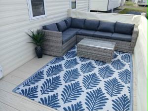 a blue couch sitting on a patio with a rug at Seascape - caravan next to Fantasy Island Ingoldmells, 2 dogs max - East Coast Holidays in Ingoldmells