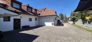 a white house with a driveway next to a building at Pokoje Gościnne Sonia in Tuszyn