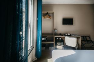 a room with a bed and a desk and a window at Hôtel Le Petit Castel in Antibes