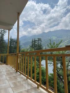 a wooden balcony with a view of the mountains at Sparrow Whisper in Jibhi