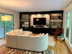 a living room with a white couch and a tv at Mid-Century Gem Creekside King Beds Near UNC in Chapel Hill