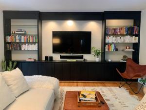 a living room with a white couch and a tv at Mid-Century Gem Creekside King Beds Near UNC in Chapel Hill
