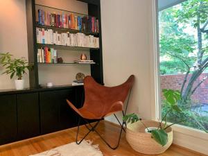 a chair in a room with a book shelf at Mid-Century Gem Creekside King Beds Near UNC in Chapel Hill +25 photos