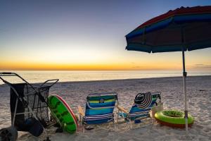 a couple of chairs and an umbrella on a beach at Waterfront Condo Beach Access & Pool Luxury in Marco Island