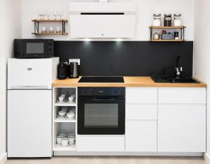 a kitchen with white cabinets and a black wall at Dream Apartments 3B KLIMATYZACJA in Oświęcim