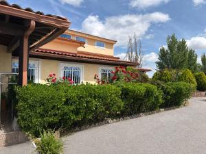 a house with bushes and flowers in front of it at Hotel Ciudad de Navalcarnero in Navalcarnero