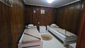 two beds in a room with wooden walls at Casa Pescărușul Vesel in Baziaş
