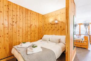 a bedroom with a large bed with wooden walls at Petit Chalet Pila in Pila