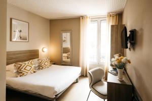 a bedroom with a bed and a chair and a window at Hôtel Le Petit Castel in Antibes