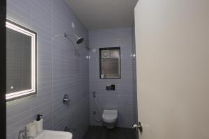 a blue tiled bathroom with a toilet and a window at Zenia IT Rooms in Pune