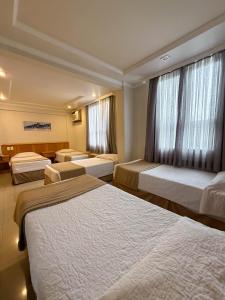 a hotel room with three beds and a window at Saionara Hotel in Rio de Janeiro