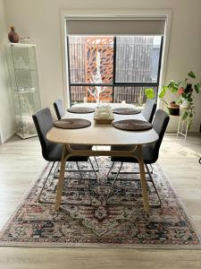 a dining room table with chairs and a rug at Cozy room with an Ensuite in Clyde North