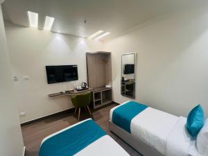 a room with two beds and a desk and a tv at Hotel Vedic Roots in Varanasi