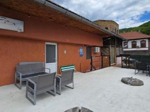 a patio with chairs and a table and a building at Casa Pescărușul Vesel in Baziaş